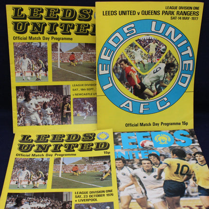 Three Leeds United football match day programmes from different years on a dark background.