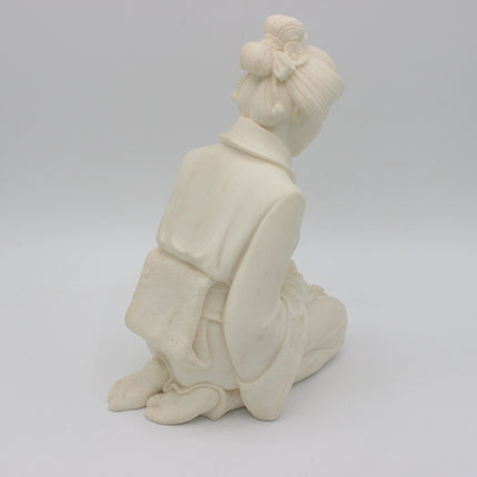 An off-white alabaster  figurine of a kneeling woman with her back turned, shown on a seamless light gray background.