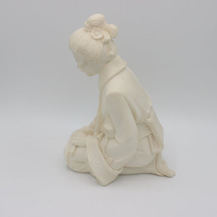 An off-white alabaster Geisha Figurine of a kneeling woman in traditional Japanese attire, shown from a side profile against a neutral light gray background.