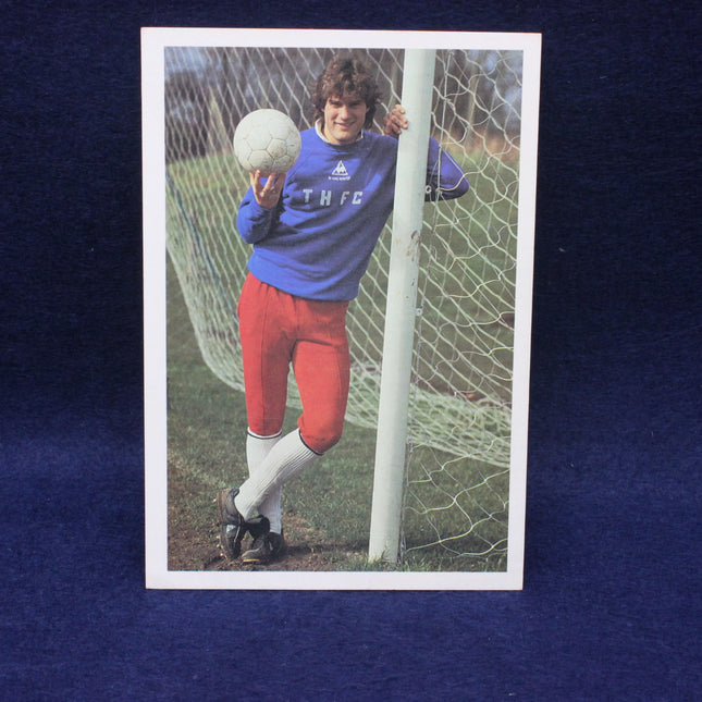 Vintage soccer card of a goalkeeper holding a ball, wearing a blue jersey and red shorts.