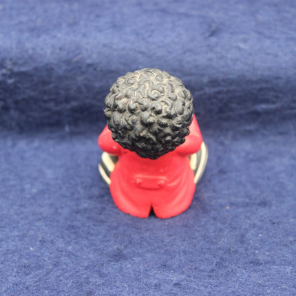 Small figurine of a Golly with a textured head on a blue fabric background