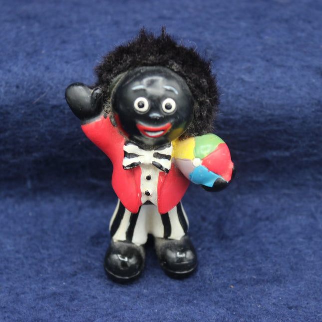 Figurine of a Golly character with a colorful ball on a blue background