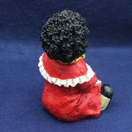 Figurine of a Golly wearing a red dress with a white collar on a blue background