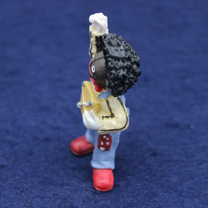 Toy figure of a Golly character with a large afro playing a guitar on a blue background