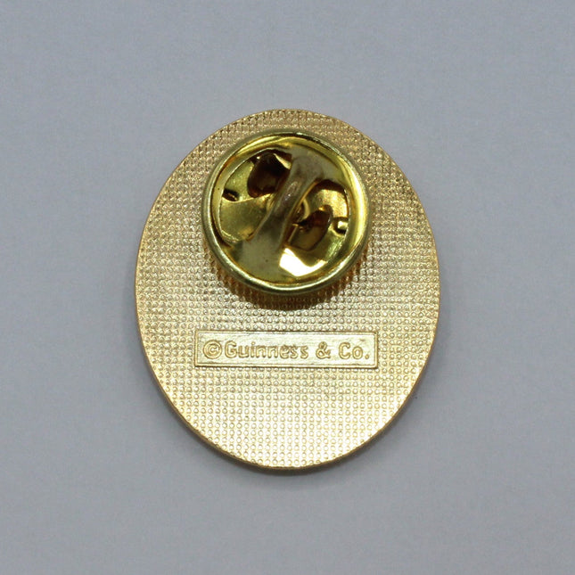 Rear of a Vintage Guinness badge on grey background