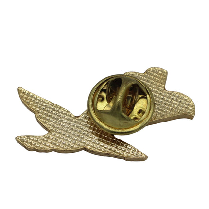 A gold-colored enamel lapel pin shaped like a flying bird, showing the back clasp mechanism on a neutral gray background.