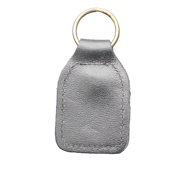 Gray leather key fob with gold ring on a blue textured background