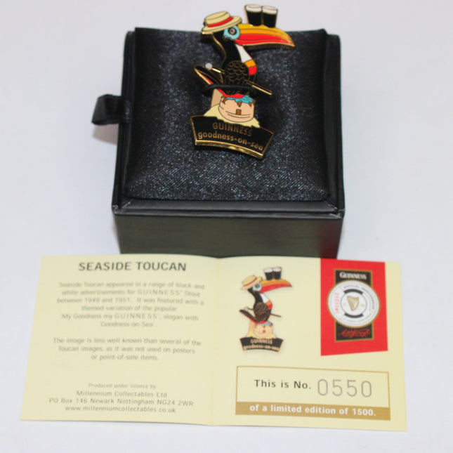 Toucan-themed collectible pin with a card in a black box on a white background