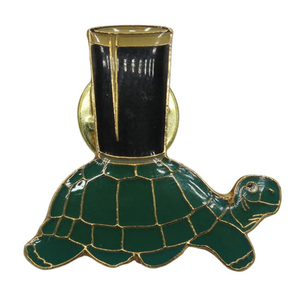 A green tortoise-shaped enamel pin with gold trim and a blackpint of Guinness on its shell, displayed against a neutral gray background.