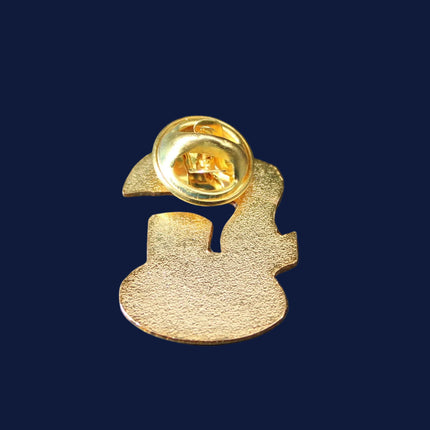 Gold-colored brooch with a unique design on a dark blue background