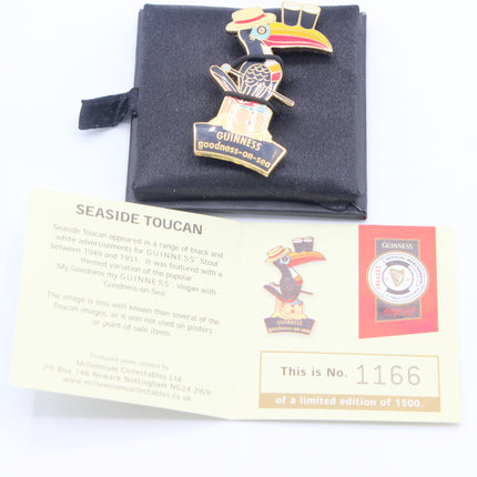 A Guinness Seaside Toucan enamel pin displayed on a black velvet pouch, with an informational card and a Guinness label below on a white background.