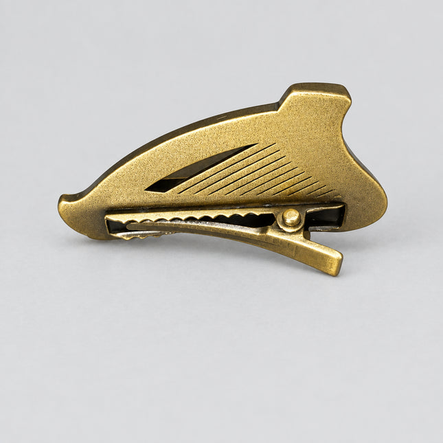A single metallic Guinness pin badge clip on a white surface