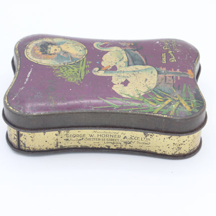 Vintage decorative metal tin with a purple lid featuring an illustrated elephant and child design, with aged cream-colored sides and printed manufacturer text on the side.