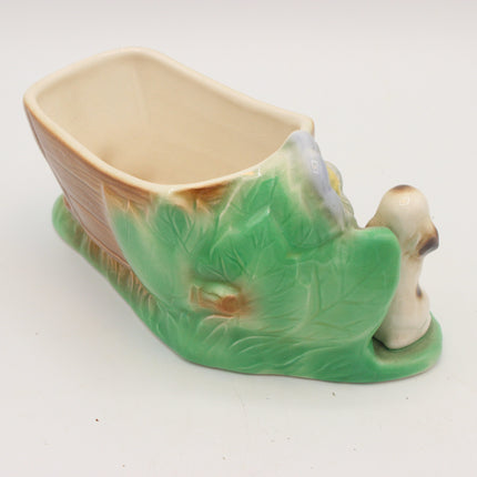 A vintage ceramic planter shaped like a small boat or shell, featuring a green leaf-textured exterior, a beige interior, and a small cream-colored bird figure attached at the front right, photographed on a white background.