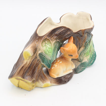 A ceramic woodland-themed planter shaped like a tree stump with a small orange-brown deer figurine nestled inside, on a plain white background.
