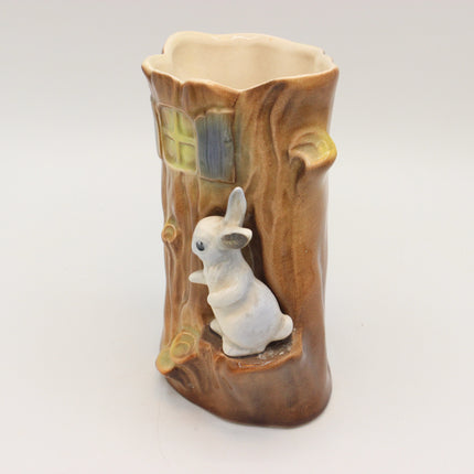 A ceramic decorative vase shaped like a tree trunk with a small white rabbit figurine sitting in the center, photographed on a plain light gray background.