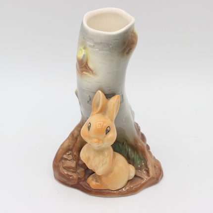 A ceramic rabbit and birch tree stump figurine on a white background.