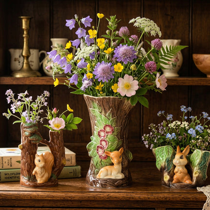 A ceramic woodland-themed tableware set featuring a large tree trunk planter with a deer and flowers, a small tree stump holder with a squirrel, and a rabbit-shaped planter, all on a white background.