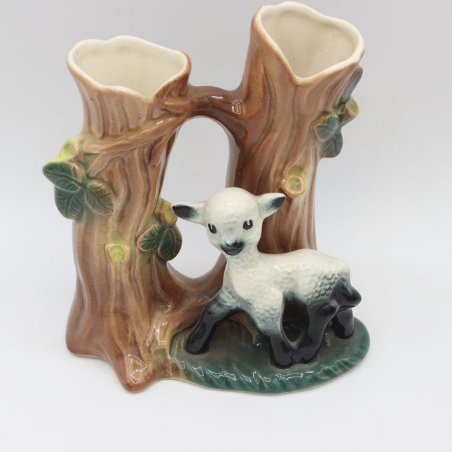 A ceramic hornsea twin posy vase designed as a tree stump arch with a small white lamb figurine at the base, photographed against a neutral light gray background.