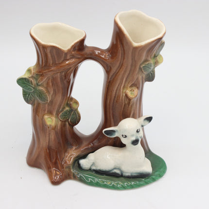 A ceramic double cup holder designed to look like a tree stump with a small white lamb figurine sitting at the base, set against a plain white background.