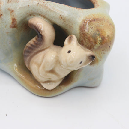 A ceramic animal figurine of a small fox or rabbit nestled inside a glazed stone-like container, shown on a plain white background.