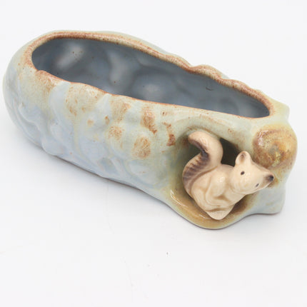 A ceramic planter shaped like a tree trunk with a small squirrel figurine emerging from one end, shown on a plain white background.