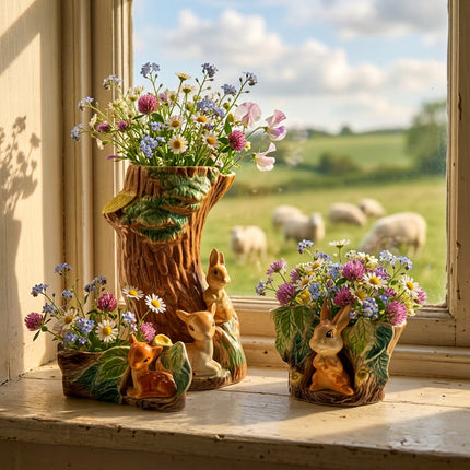 A ceramic woodland animal figurine set featuring a large tree stump with green leaves, three rabbits, and two deer in earthy brown, beige, and green glazes on a light gray background.