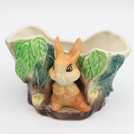 A ceramic planter shaped like a forest tree trunk with a small orange rabbit figurine in the center, green leafy sides, and a cream-colored interior, shown on a plain white background.