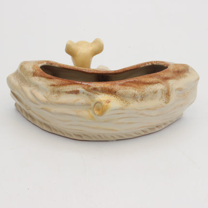 A ceramic planter shaped like a stylized tree trunk with a small bone-shaped lid on top, shown on a plain white background.