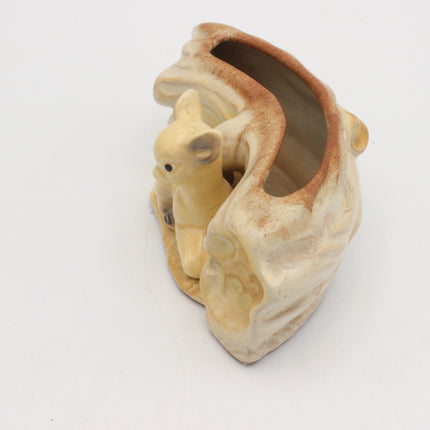 A ceramic planter shaped like a small beige animal sitting inside a rustic cream and brown pot with a glazed finish, photographed on a plain white background.