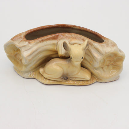 A ceramic planter shaped like a log with a small deer figurine nestled in the front, shown on a plain white background.