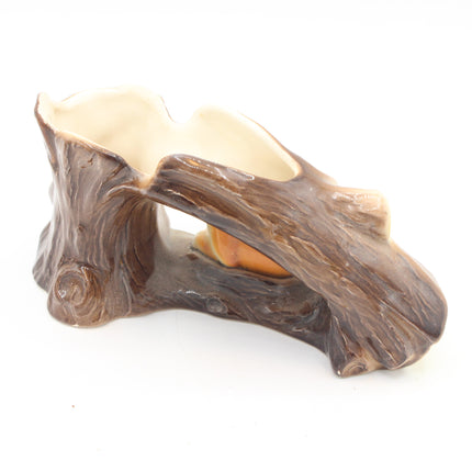 A ceramic tree stump candle holder with a textured brown bark design and a cream-colored interior, shown on a plain white background.