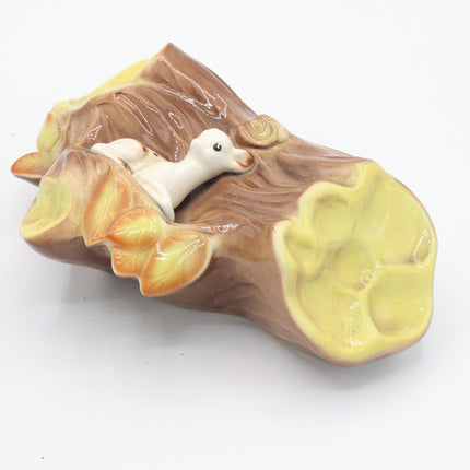 A ceramic decorative figurine shaped like a hollow log with a small white duck nestled inside, shown on a plain white background.