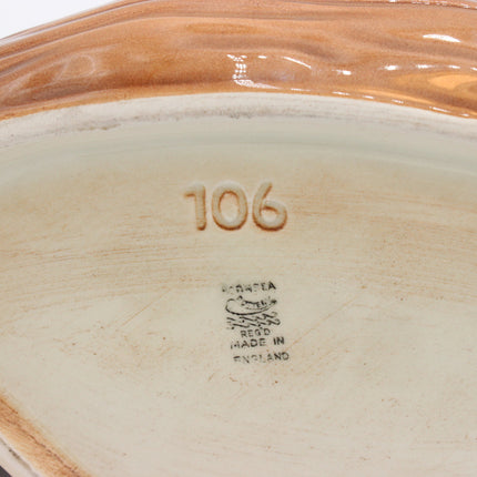 Close-up of the inside of a ceramic dish or plate showing the embossed number 106 and a maker's mark reading 'Made in England' on a warm off-white glazed surface.