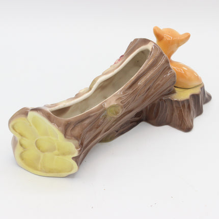 A ceramic planter shaped like a tree stump with a small orange fox figurine perched on top, photographed on a plain white background.