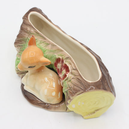 A ceramic novelty shoe shaped like a tree stump with a small deer figurine sitting beside it, photographed on a plain white background.