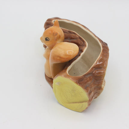 A ceramic squirrel planter shaped like a tree stump, featuring a small orange-brown squirrel figurine inside an open hollow, photographed on a plain white background.