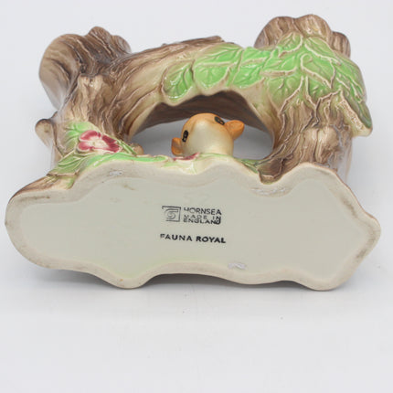 A vintage ceramic bird figurine by Hornsea England, featuring a small brown bird peeking out from beneath a tree branch with green leaves. The underside of the figurine is cream-colored with the 'HORNSEA ENGLAND' and 'FAUNA ROYAL' markings visible.