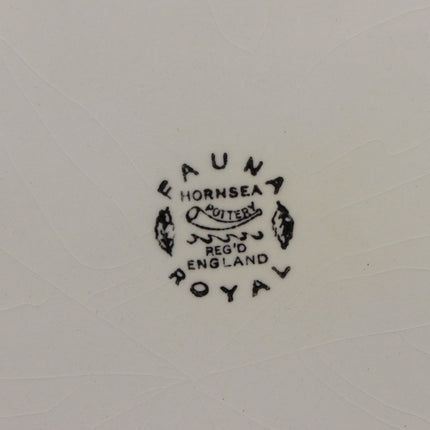 Close-up of a white ceramic surface with a black printed mark reading 'FAUNA HORNSEA ROUTE REG'D ENGLAND ROYAL' and an orange label at the bottom with handwritten text.