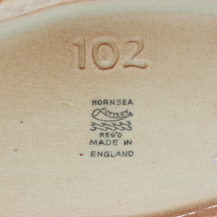 Close-up of the glazed bottom of a ceramic plate or dish, showing the embossed number 102, the Hornsea Registered Made in England mark, and a small white chip on the glaze.