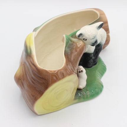 A ceramic planter shaped like a tree stump with a painted lamb figurine, shown on a plain white background.