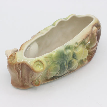 A ceramic planter shaped like a stylized tree trunk with green leafy details and a glossy glaze, photographed on a plain white background.