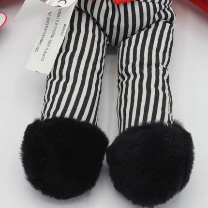 Close-up of a plush toy's striped legs with black fuzzy feet, showing a white product tag attached.