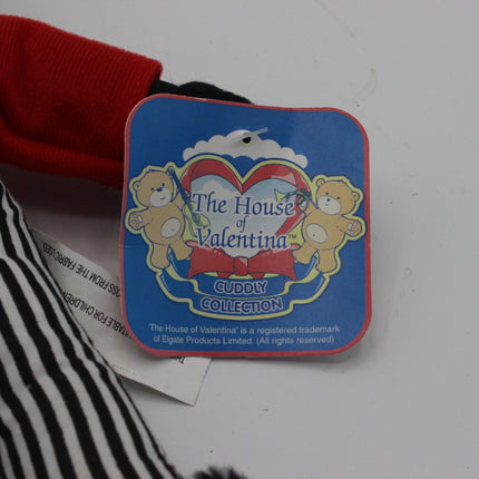 A square blue product tag for 'The House of Valentina Cuddly Collection' featuring teddy bears and a red bow, attached to a red and black striped fabric item on a white surface.