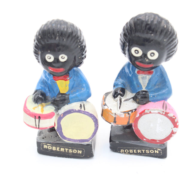 Two vintage collectible figurines of Gollies playing drums, styled after the 'Robertson' dolls, on a plain white background.