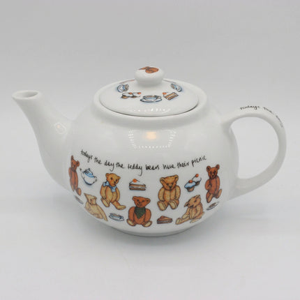A white ceramic teapot decorated with illustrations of teddy bears, teacups, cakes, and handwritten text, shown on a neutral light gray background.