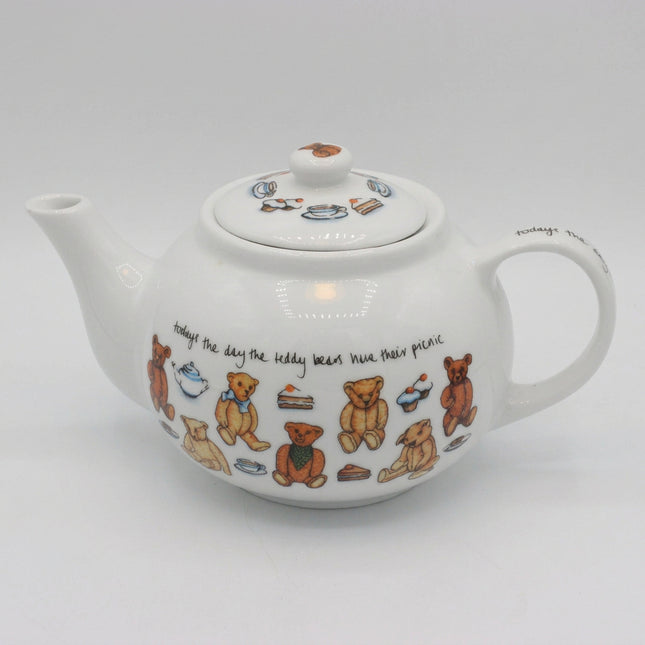 A white ceramic teapot decorated with illustrations of teddy bears, teacups, cakes, and handwritten text, shown on a neutral light gray background.