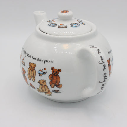 A white ceramic teapot decorated with illustrations of teddy bears, cakes, and handwritten text, shown on a plain light gray background.