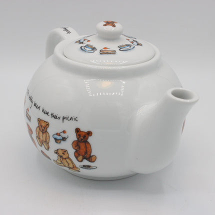 A white ceramic teapot decorated with illustrations of teddy bears, cupcakes, and small food items, shown on a plain light gray background.