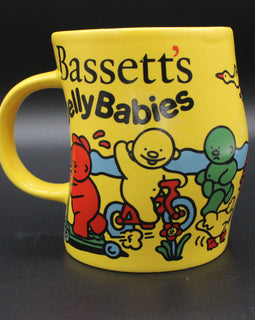 Yellow mug with cartoon characters and 'Bassetts Jelly Babies' text on a dark background